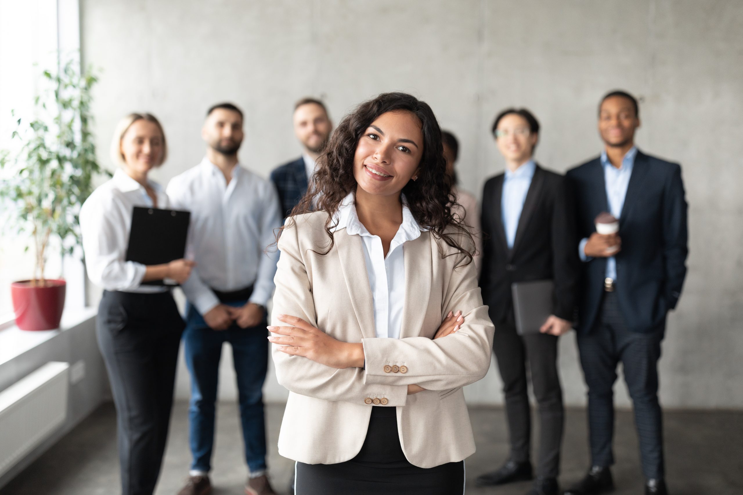 Successful Business Team. Mexican Businesswoman Standing In Front Of Her Employees Smiling To Camera Posing In Modern Office. Female Leadership, Entrepreneurship Career. Selective Focus